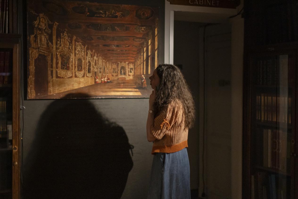 Een vrouw bekijkt geïnteresseerd een schilderij in de Nottebohmzaal