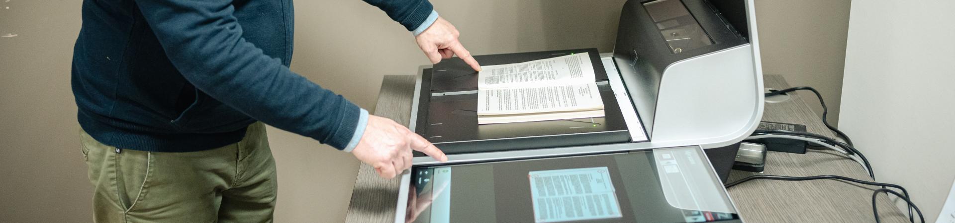 Leeszaalbezoeker gebruikt boekscanner om spread van boek in te scannen.