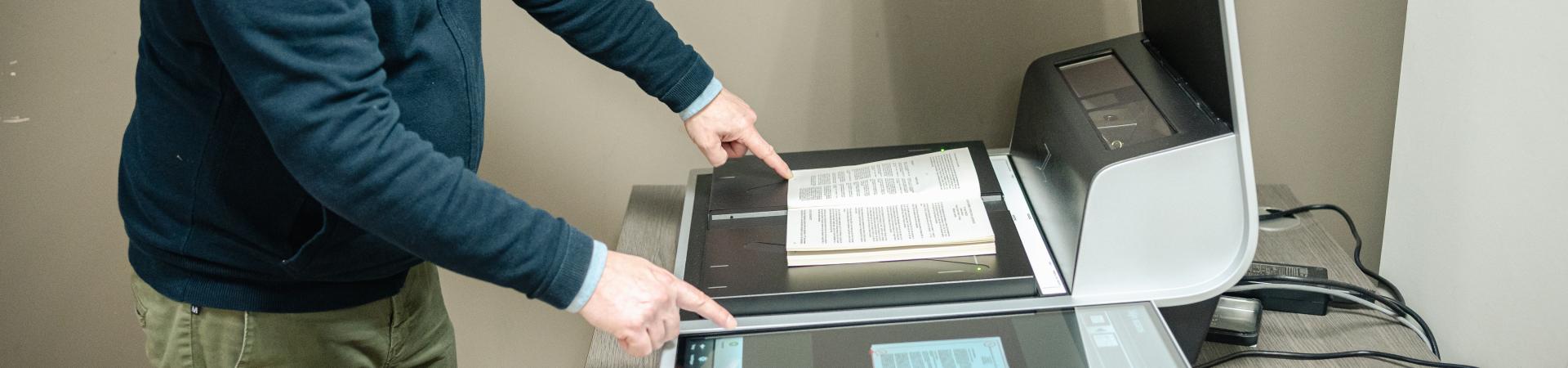 Leeszaalbezoeker gebruikt boekscanner om spread van boek in te scannen.