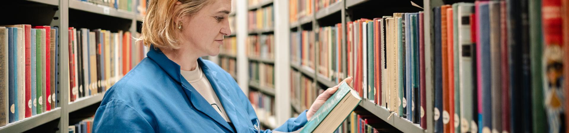 Medewerker met boek en formulier in het boekenmagazijn
