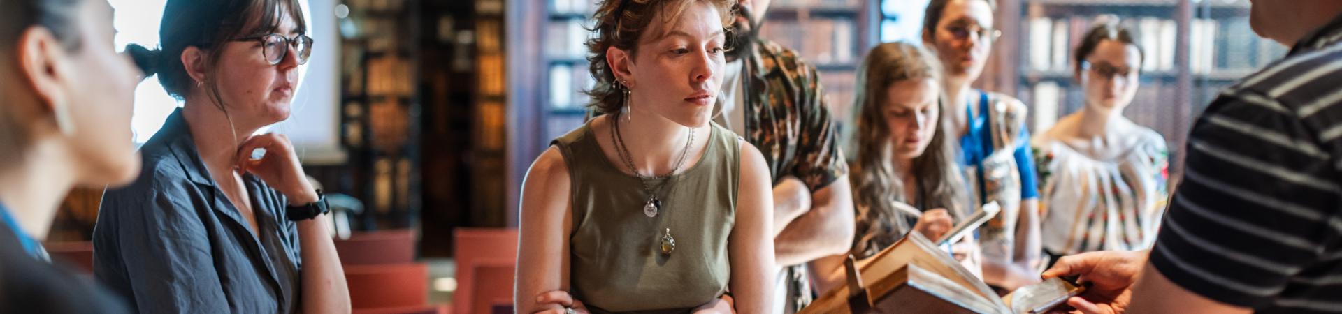 Studenten kijken naar oude druk die door conservator wordt gepresenteerd in Nottebohmzaal
