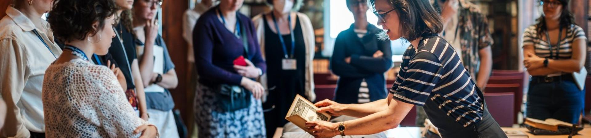 Een groep mensen luistert naar een vrouw die vertelt over een oud boek