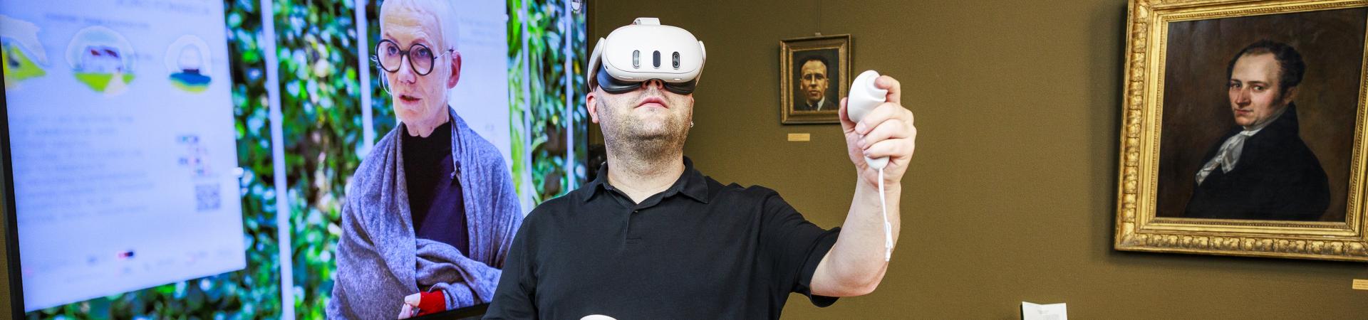 Man met een VR-bril voor een groot televisiescherm.