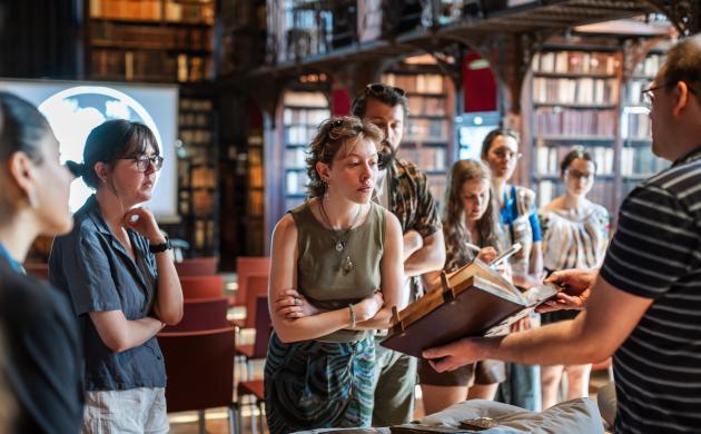Studenten kijken naar oude druk die door conservator wordt gepresenteerd in Nottebohmzaal