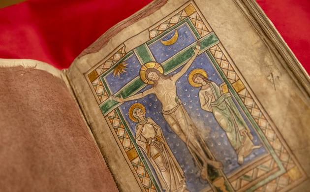 Bladvullende minatuur van de gekruisigde Christus in het midden van het boek