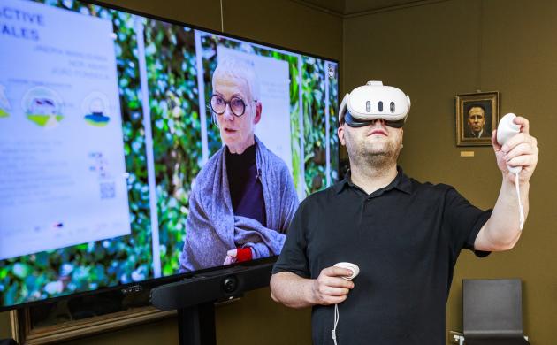 Man met een VR-bril voor een groot televisiescherm.