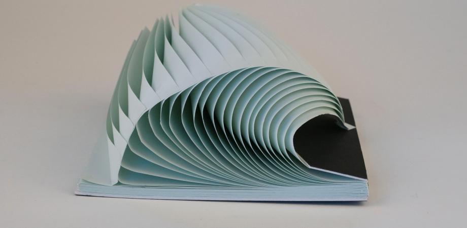 De foto toont een boekobject met blauw papier, lijkende op een golf door Tim Nijs