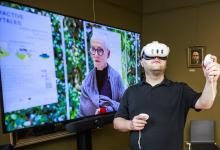 Man met een VR-bril voor een groot televisiescherm.
